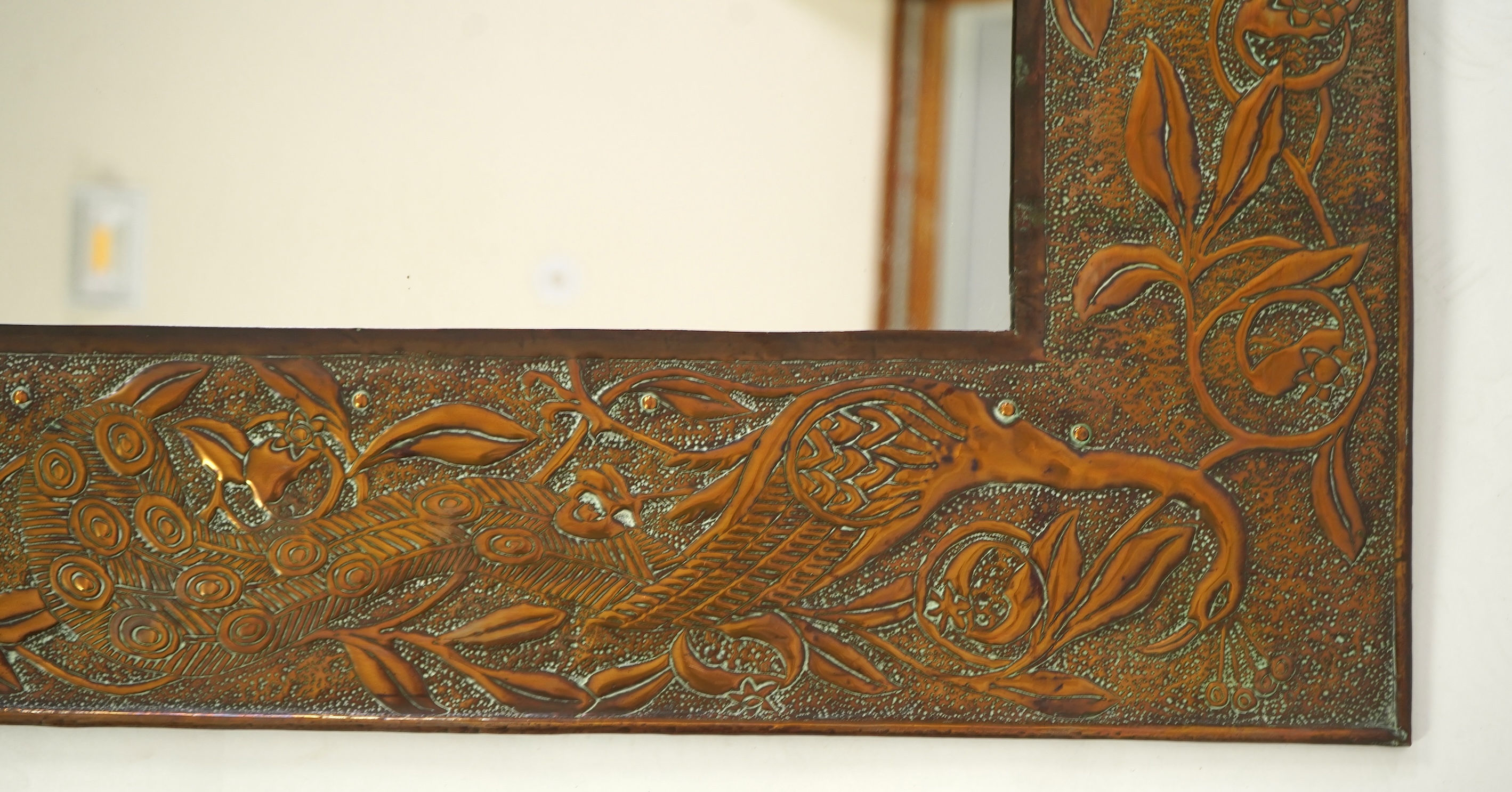 An Arts and Crafts embossed copper mirror, manner of Talwin Morris, Glasgow School